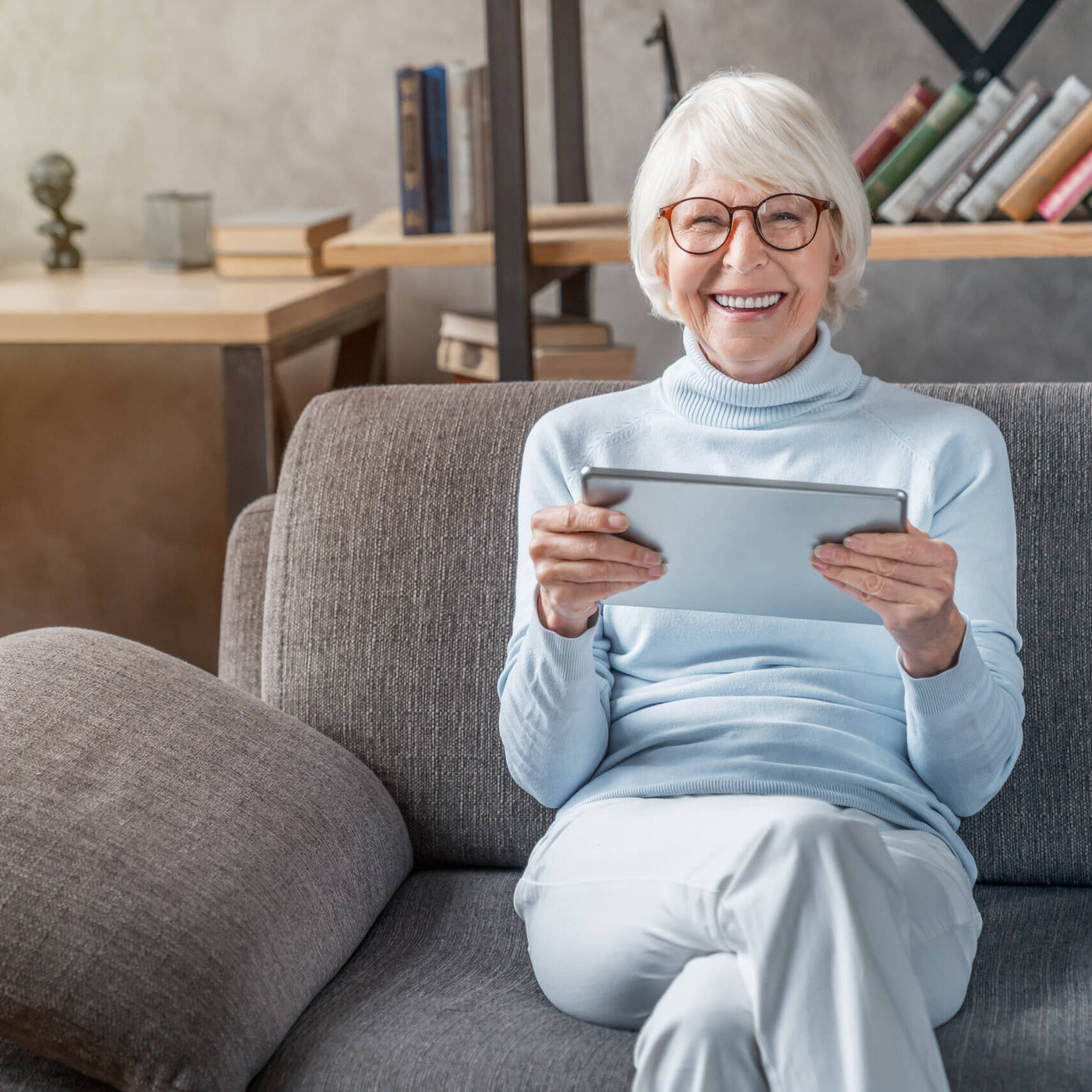 Portrait of smiling mature woman using digital tablet on sofa at home